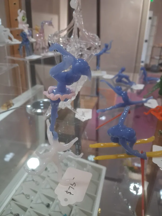 Blue glass ballerina figures with pink tutus suspended in a display case