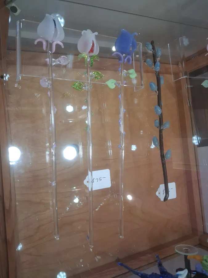 Glass flower garden stakes and a branch with blue buds in a wooden case