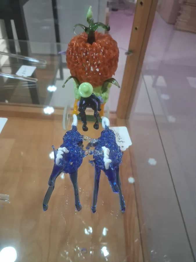 Blue glass figures with white accents beside a textured orange glass form