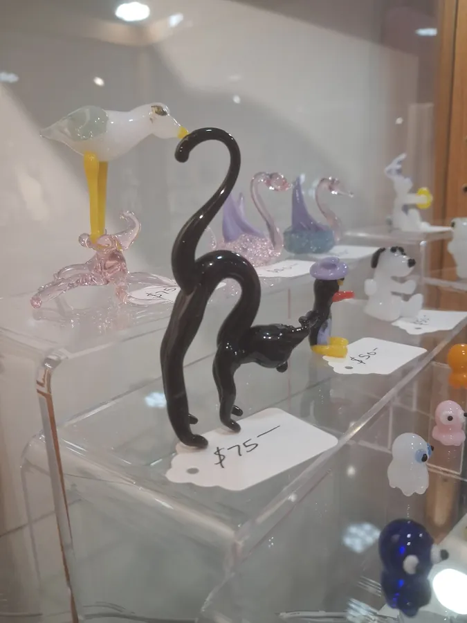Glass bird, panther, and small animal sculptures on acrylic shelves