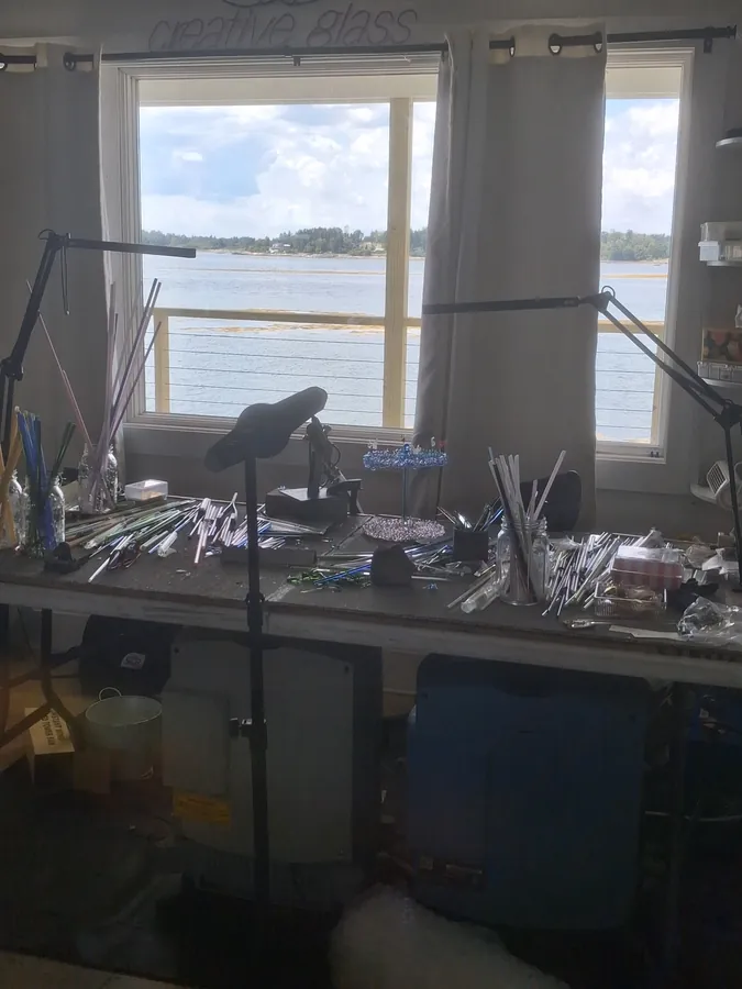 Creative Glass studio bench with tools and rods, window overlooking water, Creative Glass lettering on the wall